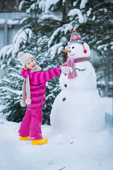 Cute girl is making a snowman. Image with selective focus