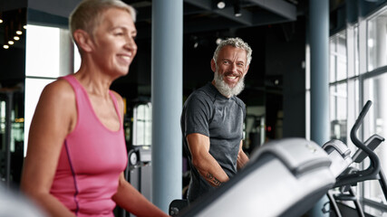 Two senior people working out on elliptical machine