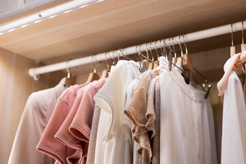 Clothes on a rail in a wardrobe. Seasonal capsule for easy dressing, order in things, cleaning out.Colorful casual clothes hang on hangers.Wardrobe, dressing room filled with clothes, shoes. storage