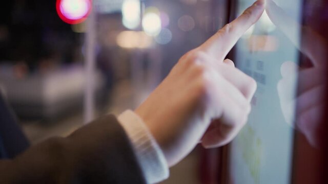 A man's hand in a coat chooses fast food on an electronic touch screen in a street food cafe close-up, side view