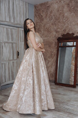 Fototapeta premium A beautiful girl in an evening dress smile shows a brick wall dress