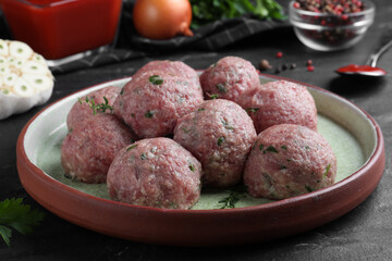 Many fresh raw meatballs on black table