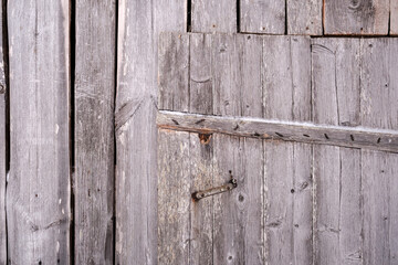 Wooden door of an old barn, with rusty nails sticking out of the boards, in the countryside. Abstract background. 