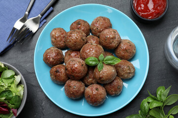 Tasty cooked meatballs with basil served on black table, flat lay