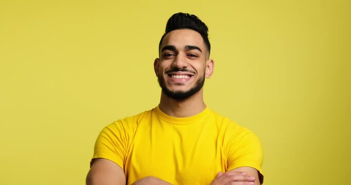 Portrait of young man smiling with arms crossed over yellow background