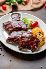 Barbecue pork ribs on dark brown concrete table side view