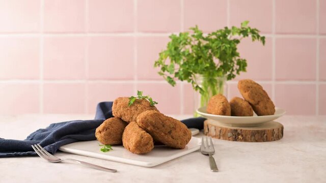 Cod dumplings, or "bolinhos de bacalhau" and parsley leaves on white ceramic dishes in a kitchen counter top.