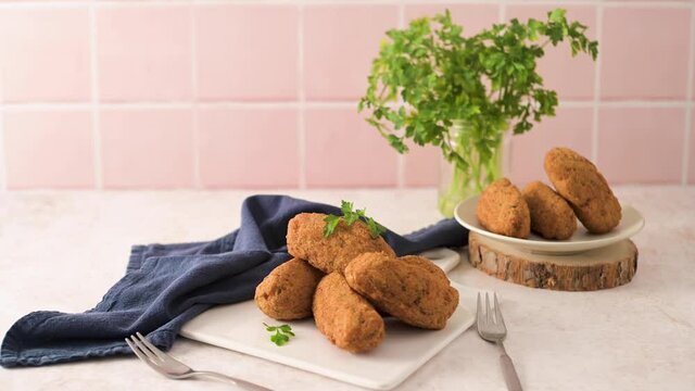 Cod dumplings, or "bolinhos de bacalhau" and parsley leaves on white ceramic dishes in a kitchen counter top.