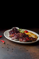 fried pork ribs with lingonberry sauce on dark brown table