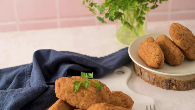 Cod dumplings, or "bolinhos de bacalhau" and parsley leaves on white ceramic dishes in a kitchen counter top.