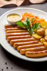 fried viennese sausages with fried cabbage and potatoes on white plate macro close up
