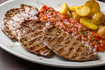 beef chops with fried potatoes and tomato sauce macro close up