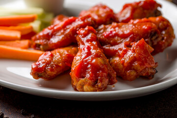 chicken wings in barbecue sauce on white plate macro close up