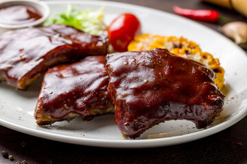 Barbecue pork ribs on dark brown concrete table side view, close up