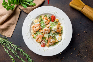 salad caesar with shrimps on dark brown concrete table top view