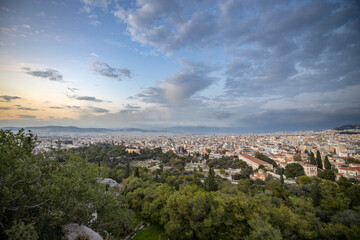 Fototapeta na wymiar View of the city of Athens November 17, 2021: Evening landscape, blue sky with clouds, soft light. Picturesque view from the hill to the old town.