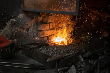 blacksmith warming blank metal on coal fire