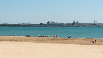 Fototapeta na wymiar People sunbathing on the beach with the Rota military base in the background, Cadiz, Andalusia, Spain