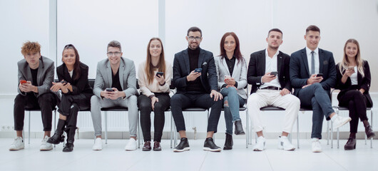 group of diverse young business people looking at their smartphone screens.