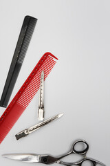 two professional flat combs, professional scissors and metal clips close-up on a white background