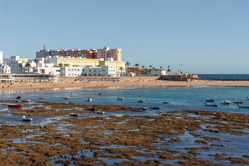 Boats docked in La Caleta beach in Cadiz Bay at low tide, Andalusia, Spain