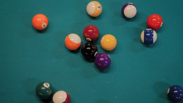 Slow motion, top view: breaking racked colorful pool balls on teal billiard table - close up. Sport, game, competition, hobby and leisure time concept