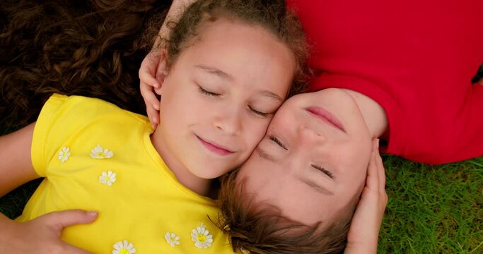 Little hunny boy and girl looks at sky. Smile of Children and look up to camera. Happy little brother and sister lies on green grass. Children is dream on the grass in park. Happy face of baby