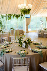 Event and catering agency organization modern wedding in nature style.Table for guests assembled with dishes, cutlery, glasses and flowers, candles and elements, chairs in restaurant