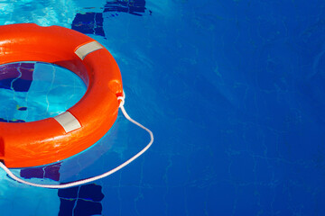 Red lifebuoy in the pool on blue water on a sunny day, copy space