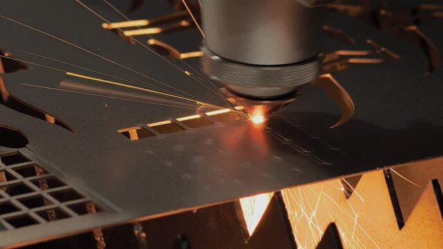 CNC laser cutting machine working with sheet metal with sparks at factory, plant - close up, slow motion. Metalworking, machining, industrial, equipment, technology and manufacturing concept