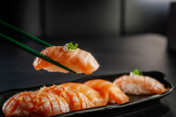 Blowtorcherd salmon onigiri on chopsticks.