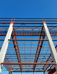 metal structure of a building on concrete columns against a blue sky background, construction process, construction stage