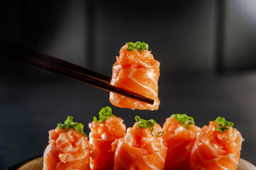 Salmon Jhow sushi on chopsticks.
