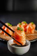 Salmon Jhow sushi on chopsticks.