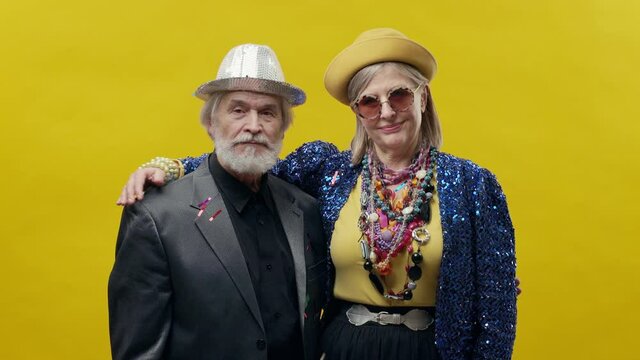 Elderly Man And Woman. Stylish Elderly Woman On Yellow Background. She Is Wearing Hat And Glasses. Stylish Man With Beard In Hat.