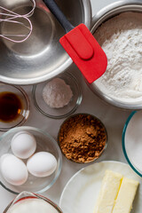 Looking down on ingredients for baking a basic chocolate cake.  Ingredients include flour, sugar, butter, milk, eggs, cocoa, baking powder, and vanilla.