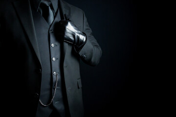 Portrait of Mysterious Man in Dark Suit and Leather Gloves on Black Background. Vintage Style and...