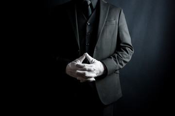 Portrait of Man in Dark Suit and White Gloves Standing on Black Background. Elegant Service and Professional Hospitality. - obrazy, fototapety, plakaty