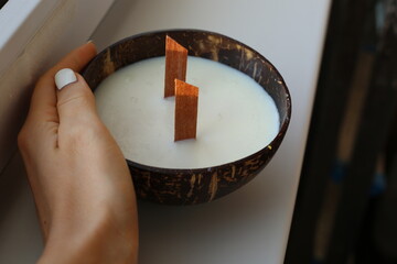 Handmade soy wax candle in coconut shell on white background.