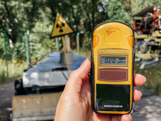 In the hand is a dosimeter that measures the level of radiation against the background of the city...