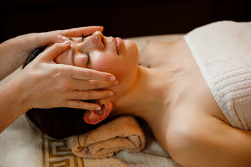 Obraz na płótnie Canvas Young woman in a spa salon. Facial massage procedure.