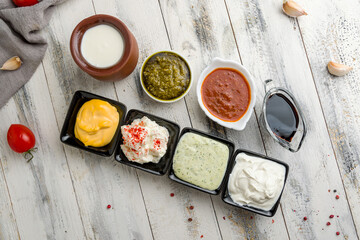 assorted sauces top view on white wooden table