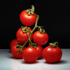 Several tomatoes on a green branch
