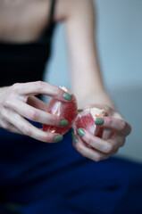 Female hands hold pieces of grapefruit. The girl peels a ripe fruit. Copy space.