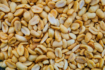 Salted roasted peanuts with spices close-up. Very salty snack with visible salt crystals.