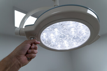 Doctor's hand holding a lit surgical light in a hospital operating room