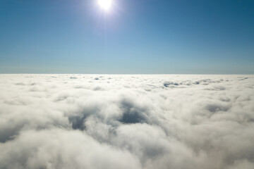 Aerial view from above of white puffy clouds in bright sunny day.