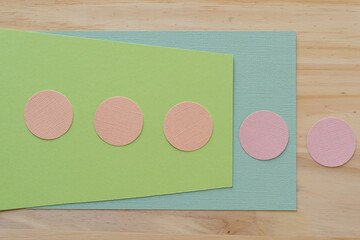 paper circles on green cards on a wooden surface