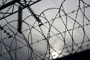 Razor wire close-up. A dark silhouette against a stormy sky.