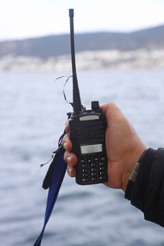 A man holds a portable walkie-talkie in his hand to communicate with other people in winter. The method of communication for winter fishing.